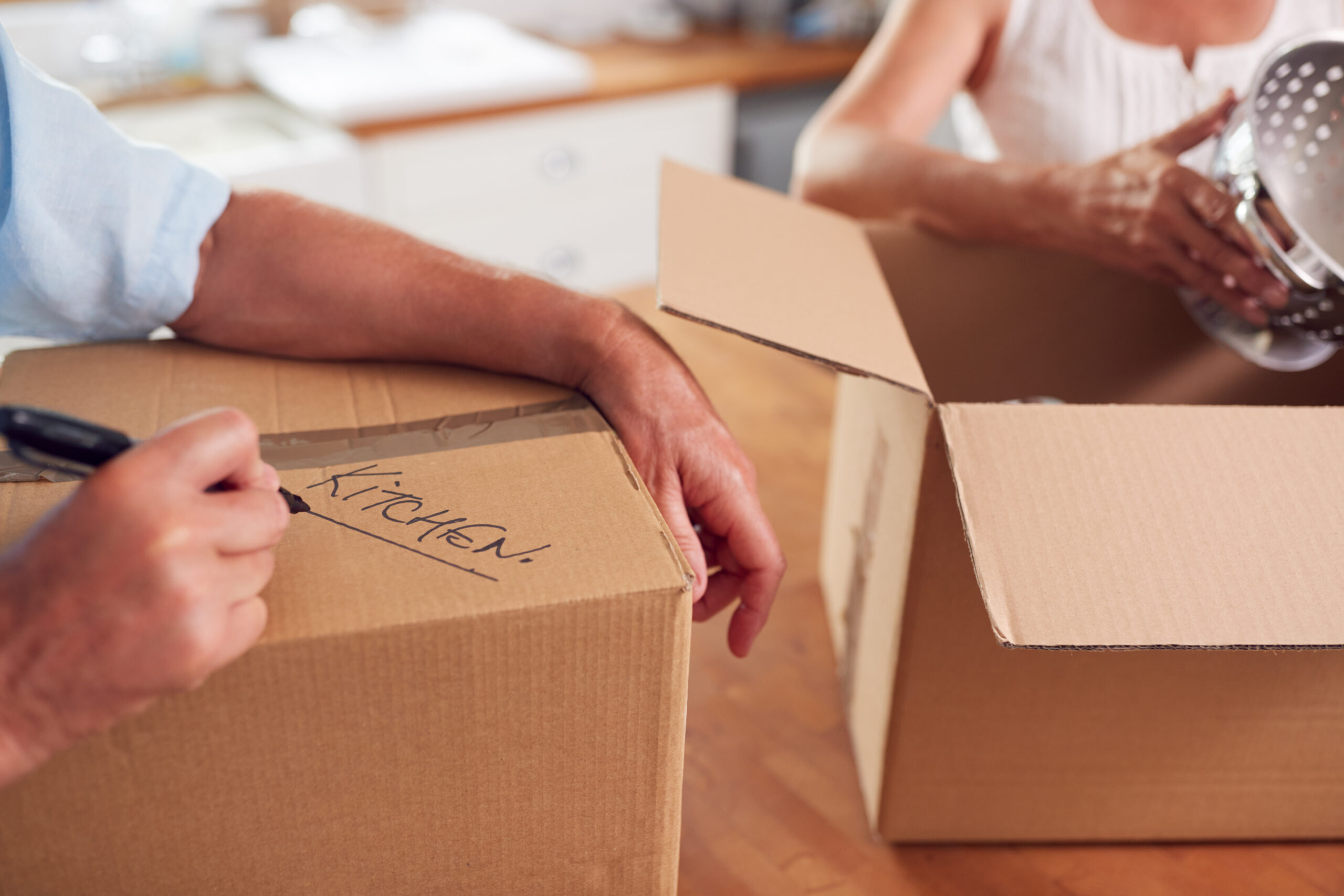 senior downsizing into a retirement community by packing up personal items into boxes